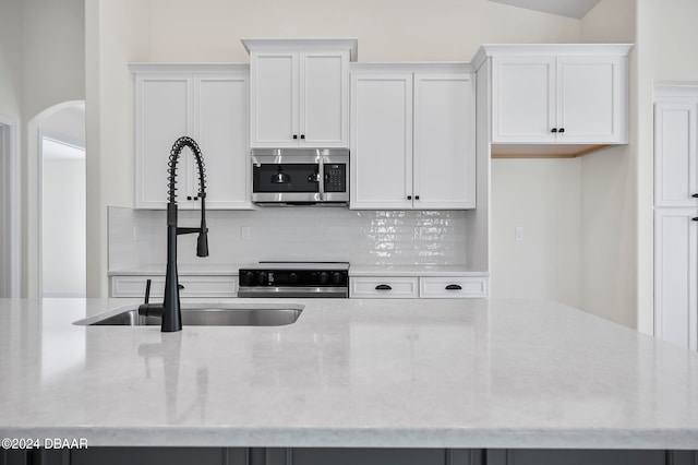 kitchen with decorative backsplash, white cabinets, sink, and stainless steel appliances