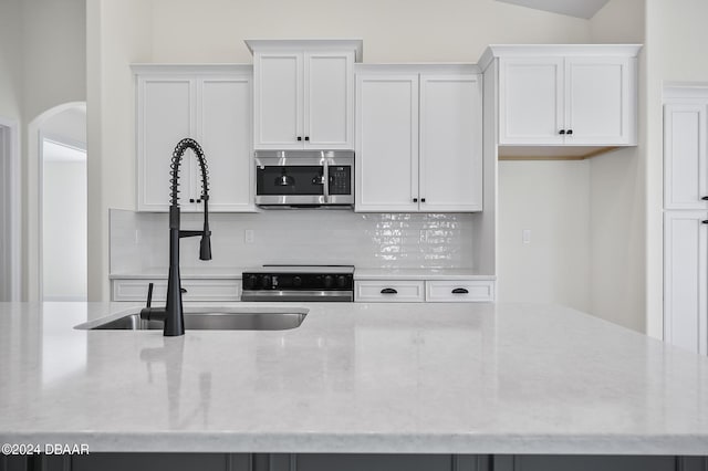 111 Bird Of Paradise Dr, Palm Coast, FL 32137 - kitchen with stainless steel microwave, a sink, white cabinetry, range, and tasteful backsplash