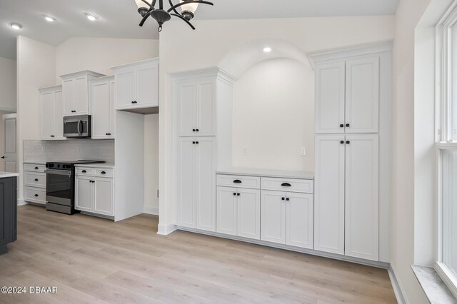 kitchen with white cabinets, appliances with stainless steel finishes, vaulted ceiling, and light hardwood / wood-style flooring