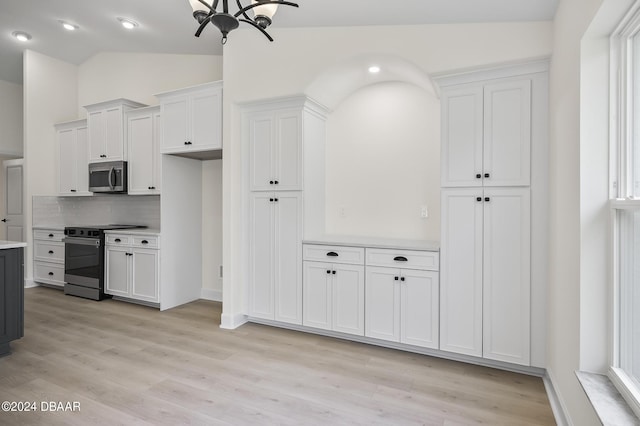 111 Bird Of Paradise Dr, Palm Coast, FL 32137 - kitchen with stainless steel microwave, range with electric cooktop, light countertops, light wood-style floors, and vaulted ceiling