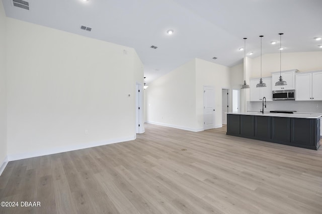 111 Bird Of Paradise Dr, Palm Coast, FL 32137 - kitchen featuring stainless steel microwave, open floor plan, light countertops, white cabinetry, and a sink