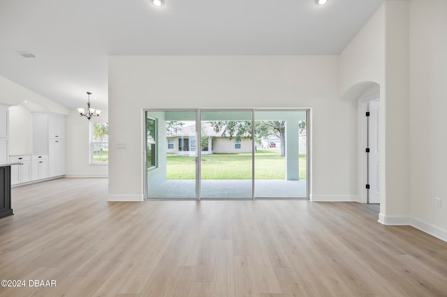 empty room featuring a notable chandelier and light hardwood / wood-style flooring