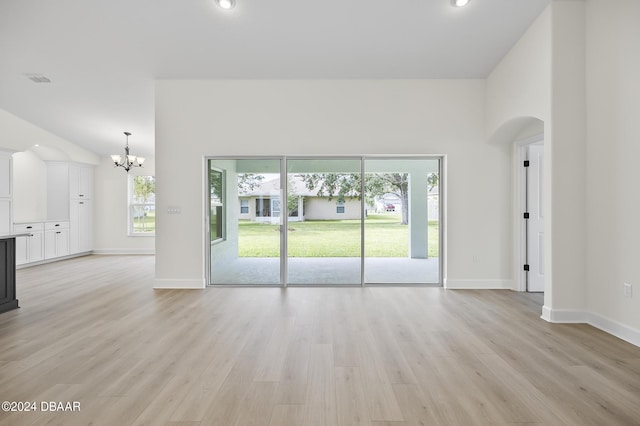 111 Bird Of Paradise Dr, Palm Coast, FL 32137 - unfurnished living room with a chandelier, arched walkways, light wood-style floors, baseboards, and recessed lighting