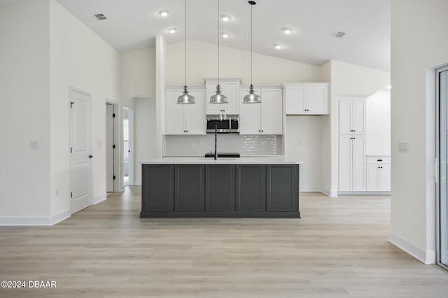 111 Bird Of Paradise Dr, Palm Coast, FL 32137 - kitchen featuring stainless steel microwave, white cabinets, light countertops, light wood finished floors, and high vaulted ceiling