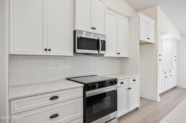 kitchen with white cabinets, light wood-type flooring, appliances with stainless steel finishes, and tasteful backsplash