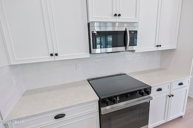 kitchen featuring tasteful backsplash, appliances with stainless steel finishes, light hardwood / wood-style floors, and white cabinets