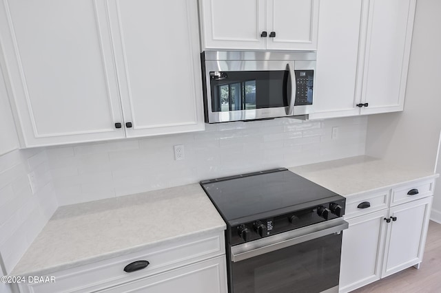 111 Bird Of Paradise Dr, Palm Coast, FL 32137 - kitchen with appliances with stainless steel finishes, white cabinetry, tasteful backsplash, and light stone counters