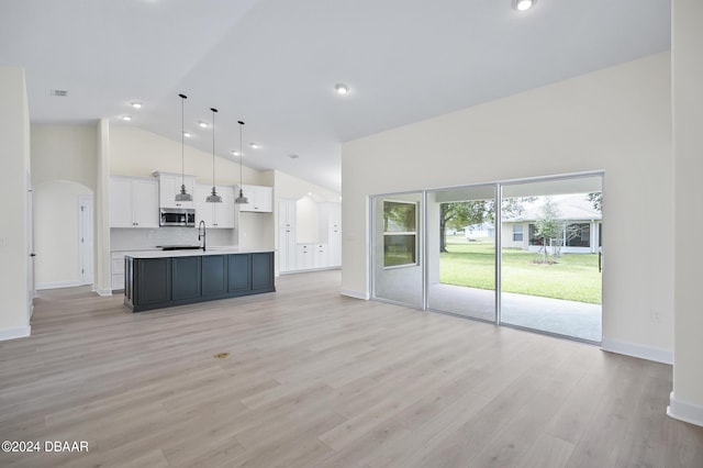 111 Bird Of Paradise Dr, Palm Coast, FL 32137 - kitchen featuring stainless steel microwave, white cabinetry, open floor plan, a kitchen island with sink, and high vaulted ceiling
