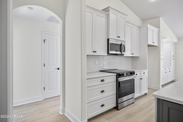 111 Bird Of Paradise Dr, Palm Coast, FL 32137 - kitchen featuring stainless steel appliances, light wood finished floors, light countertops, decorative backsplash, and baseboards