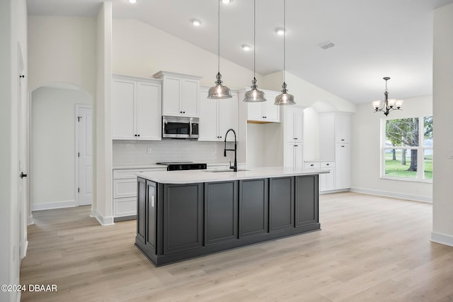 kitchen with light hardwood / wood-style floors, a center island with sink, sink, white cabinetry, and hanging light fixtures