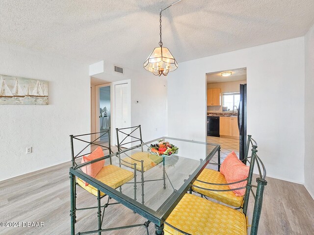 3606 S Peninsula Dr # 404, Port Orange, FL 32127 - dining room with light wood-style floors, a chandelier, and a textured ceiling