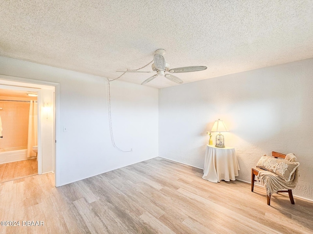 unfurnished room featuring ceiling fan, light hardwood / wood-style floors, and a textured ceiling