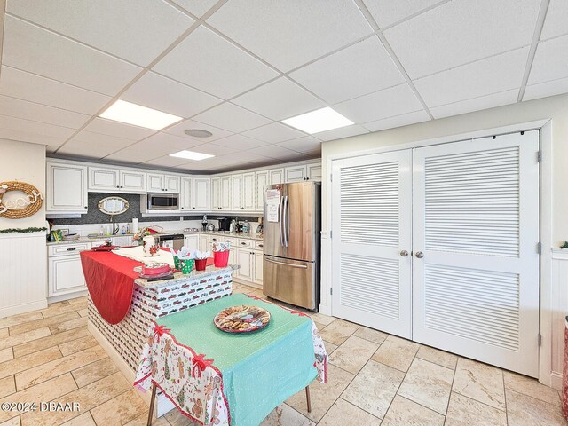 3606 S Peninsula Dr # 404, Port Orange, FL 32127 - kitchen featuring appliances with stainless steel finishes, a drop ceiling, light countertops, white cabinets, and a center island