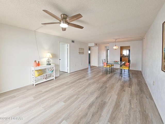 interior space with a textured ceiling, light wood-type flooring, and ceiling fan