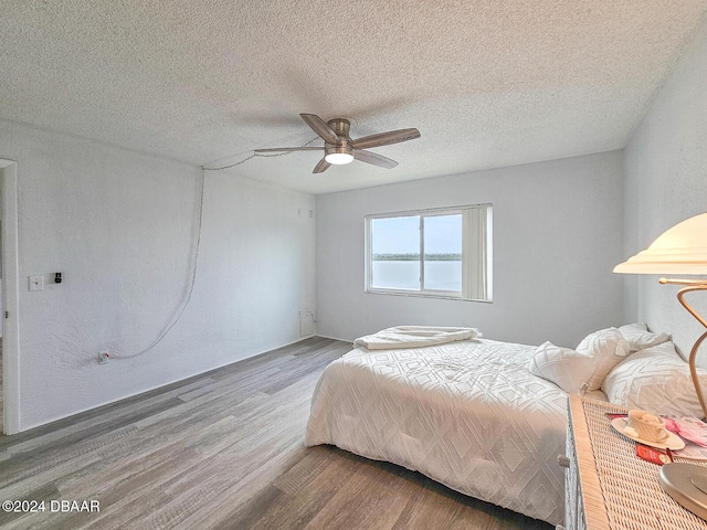 bedroom with hardwood / wood-style flooring, ceiling fan, and a textured ceiling