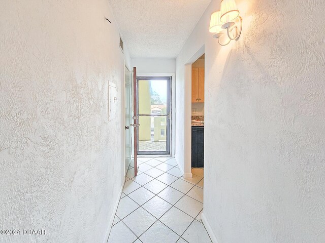 3606 S Peninsula Dr # 404, Port Orange, FL 32127 - hallway featuring a textured wall, light tile patterned floors, and a textured ceiling