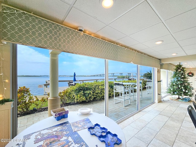 sunroom featuring a drop ceiling, a water view, and plenty of natural light