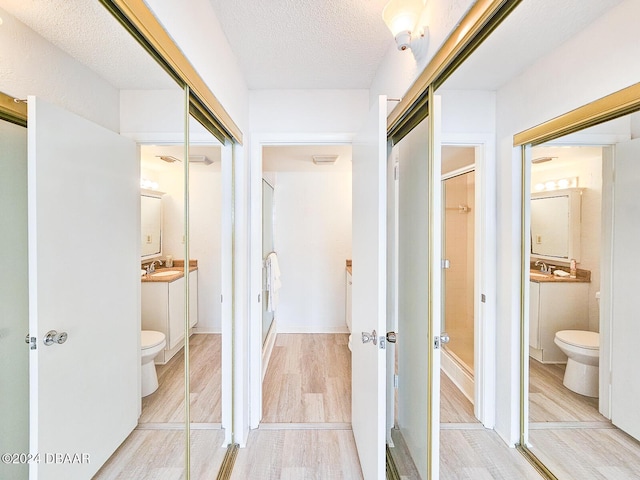 bathroom featuring vanity, toilet, wood-type flooring, and a textured ceiling