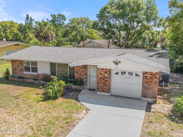 ranch-style house featuring a garage, central AC, and a front yard