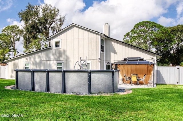 back of property featuring a pool, a gazebo, and a lawn