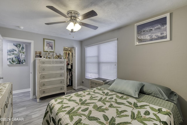 bedroom with ceiling fan, a spacious closet, light hardwood / wood-style floors, and a closet