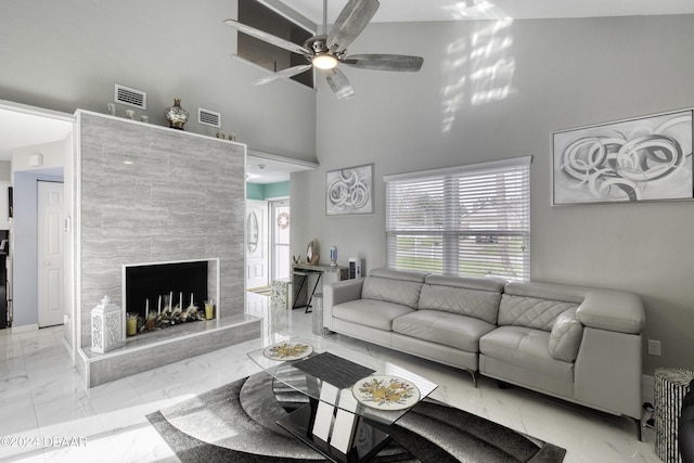 living room with ceiling fan, a premium fireplace, and a towering ceiling