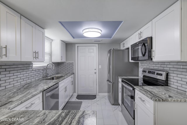 kitchen featuring stainless steel appliances, sink, white cabinets, and light stone counters