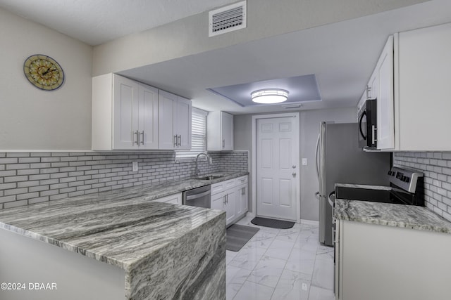 kitchen with light stone counters, stainless steel dishwasher, kitchen peninsula, and white cabinets