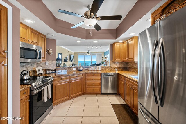 3145 S Atlantic Ave Unit 504, Daytona Beach Shores, FL 32118 - kitchen with appliances with stainless steel finishes, a tray ceiling, a ceiling fan, backsplash, and recessed lighting