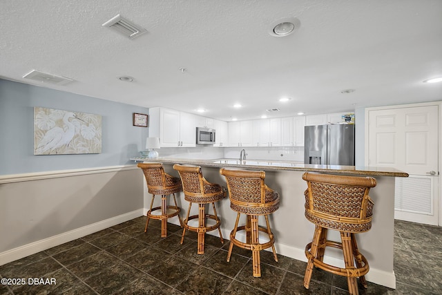 3145 S Atlantic Ave Unit 504, Daytona Beach Shores, FL 32118 - kitchen featuring stainless steel appliances, a kitchen breakfast bar, white cabinets, a peninsula, and recessed lighting