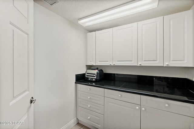 3145 S Atlantic Ave Unit 504, Daytona Beach Shores, FL 32118 - kitchen featuring dark countertops, white cabinetry, a textured ceiling, and light tile patterned flooring