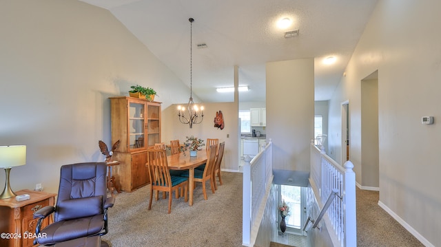 carpeted dining room with an inviting chandelier and high vaulted ceiling