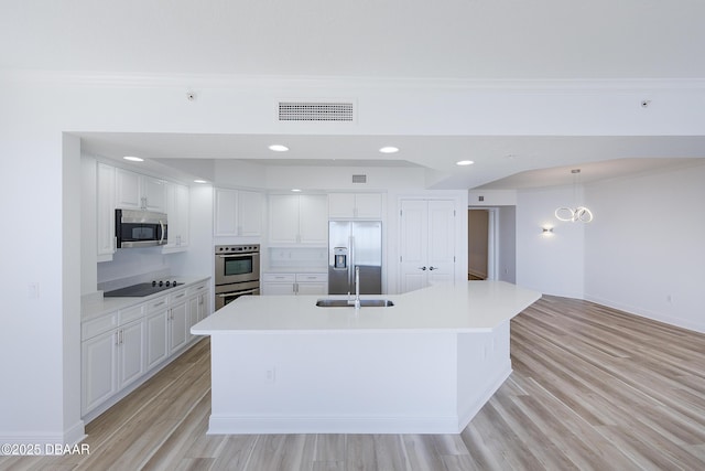 kitchen featuring sink, a kitchen island with sink, stainless steel appliances, light hardwood / wood-style floors, and white cabinets