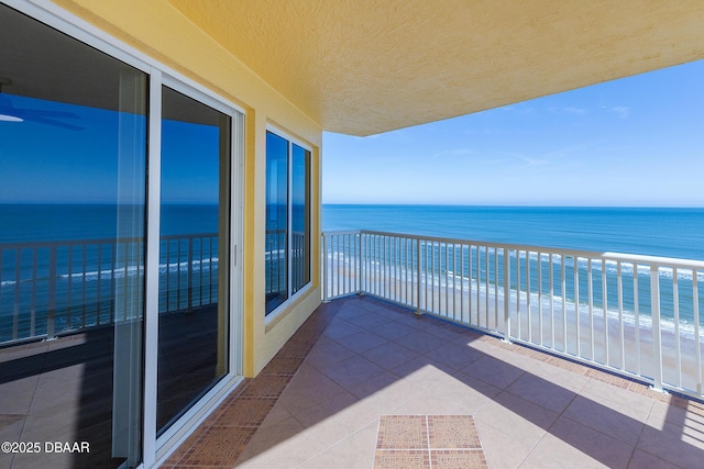 balcony with a water view and a view of the beach