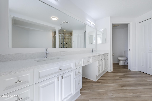 bathroom featuring a shower with door, vanity, wood-type flooring, and toilet