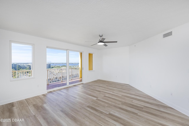 spare room with ceiling fan, a textured ceiling, and light hardwood / wood-style floors