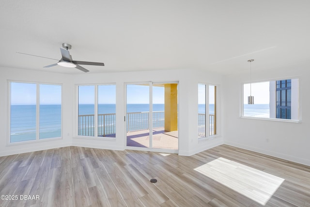 unfurnished room featuring ceiling fan, a water view, and light wood-type flooring