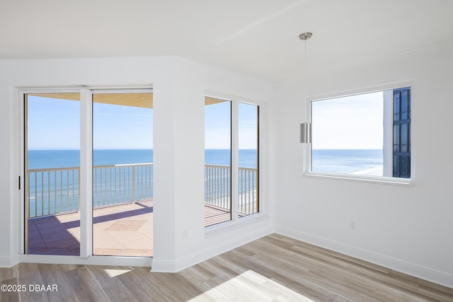 spare room with a water view and light hardwood / wood-style floors