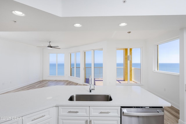 kitchen with sink, a water view, white cabinetry, decorative light fixtures, and stainless steel dishwasher