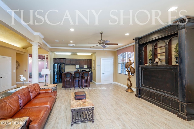 living room featuring ornate columns, crown molding, ceiling fan, and light hardwood / wood-style flooring