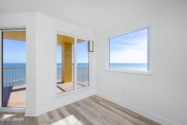 unfurnished room with a water view and light hardwood / wood-style floors