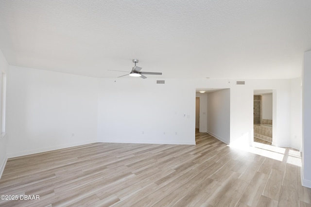 unfurnished room with ceiling fan, light hardwood / wood-style flooring, and a textured ceiling