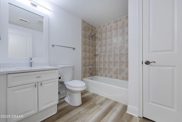 full bathroom with toilet, a textured ceiling, vanity, tiled shower / bath combo, and hardwood / wood-style floors