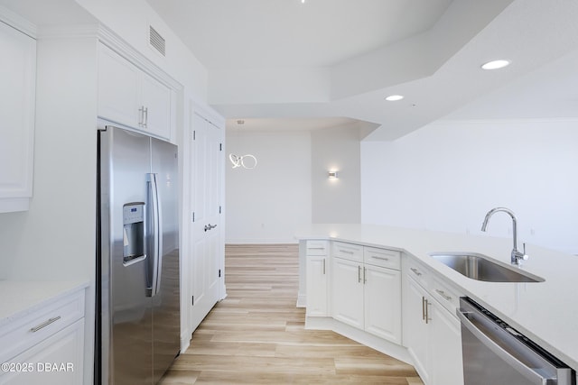 kitchen with white cabinetry, stainless steel appliances, sink, and light hardwood / wood-style flooring