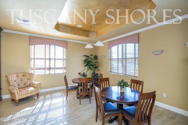 dining area with a raised ceiling, crown molding, and hardwood / wood-style floors