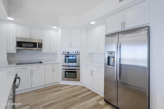 kitchen featuring light stone countertops, white cabinetry, appliances with stainless steel finishes, and light hardwood / wood-style flooring