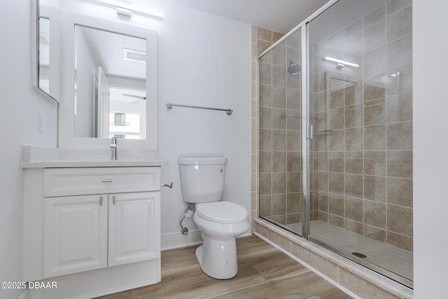 bathroom with hardwood / wood-style floors, vanity, toilet, and walk in shower