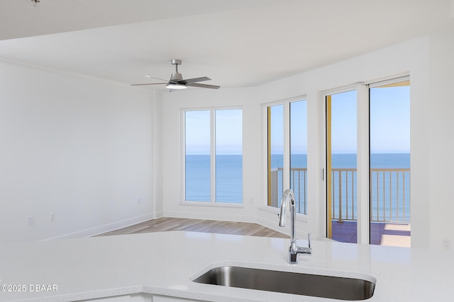 kitchen with a water view, sink, ceiling fan, and light hardwood / wood-style flooring