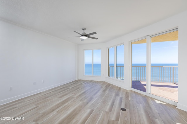 empty room with ceiling fan, a water view, and light wood-type flooring