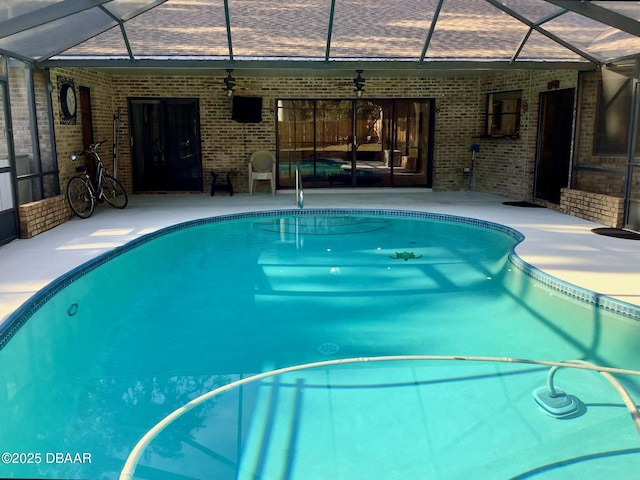 view of pool with a patio, ceiling fan, and glass enclosure